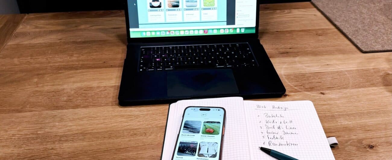 Laptop, iPhone mit der neuen Startseite und ein Notizbuch mit der Liste der sechs Themenwelten auf einem Holztisch